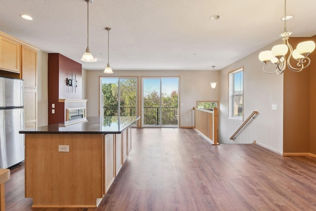 kitchen featuring pendant lighting, stainless steel refrigerator, dark wood-type flooring, and a textured ceiling