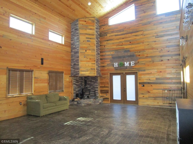 unfurnished living room with wood walls, a wood stove, high vaulted ceiling, french doors, and wood ceiling