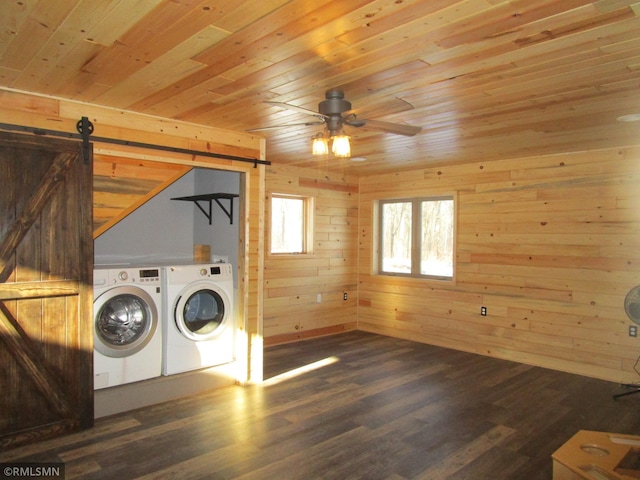 clothes washing area featuring dark wood-type flooring, wood ceiling, wooden walls, independent washer and dryer, and a barn door