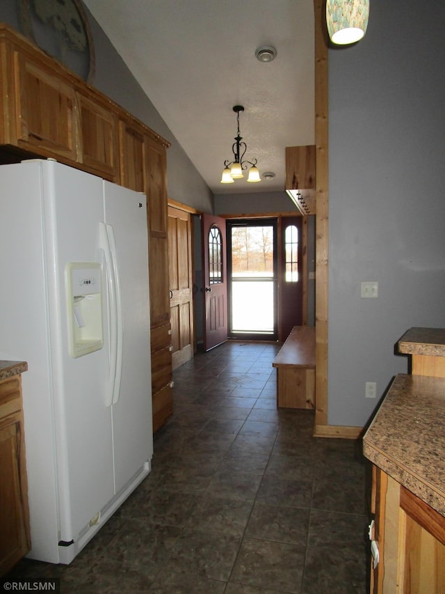 kitchen with hanging light fixtures, vaulted ceiling, white fridge with ice dispenser, and a notable chandelier