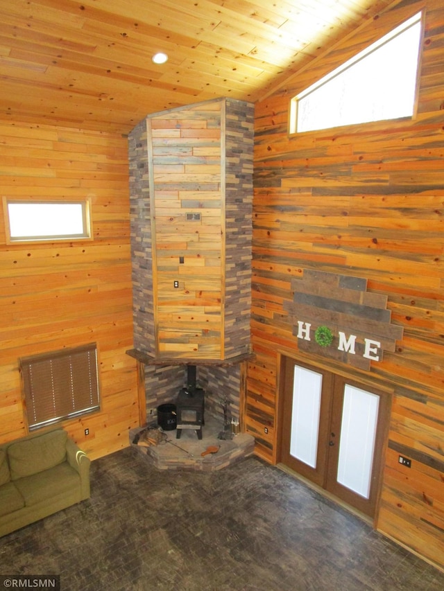 unfurnished living room with lofted ceiling, wood walls, wood ceiling, visible vents, and a wood stove