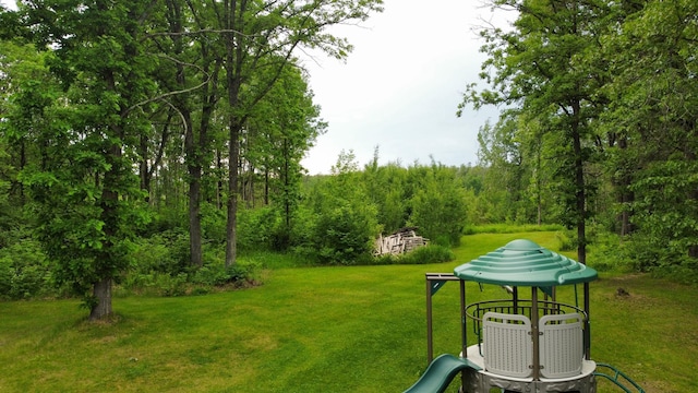 view of yard with a wooded view and playground community