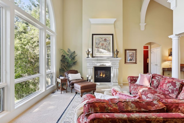 carpeted living room featuring a high ceiling, ornate columns, and a healthy amount of sunlight