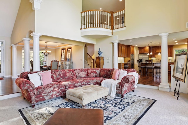 living room with light carpet, a towering ceiling, an inviting chandelier, and ornamental molding