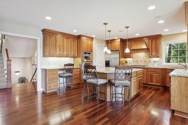 kitchen featuring a kitchen island, appliances with stainless steel finishes, dark wood-type flooring, and decorative light fixtures