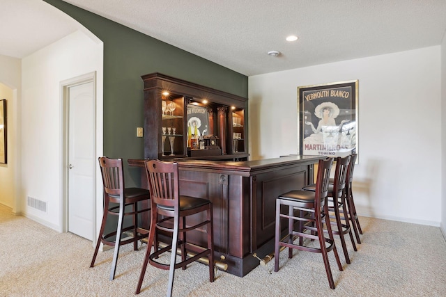 bar with a textured ceiling and light colored carpet