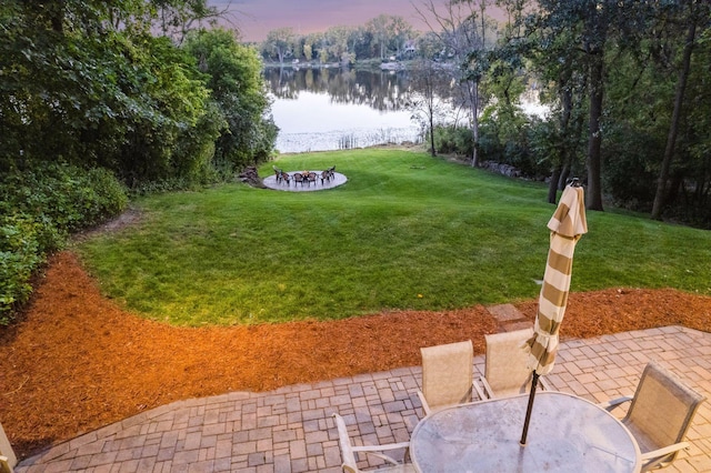 yard at dusk featuring a patio area and a water view