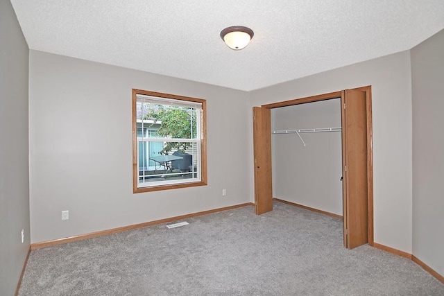 unfurnished bedroom featuring baseboards, a textured ceiling, visible vents, and light colored carpet