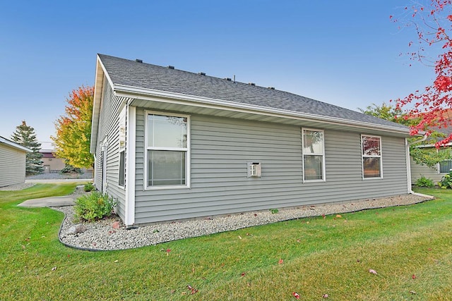 view of home's exterior with roof with shingles and a yard