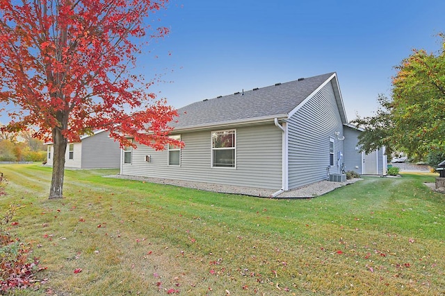 back of house with roof with shingles and a yard