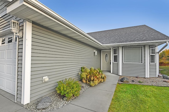 property entrance with roof with shingles and an attached garage