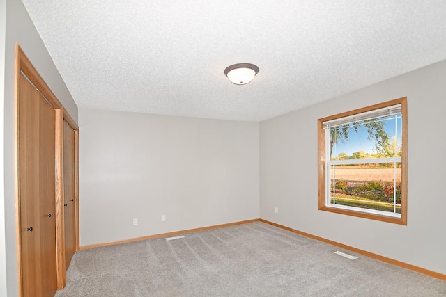 unfurnished bedroom with light carpet, visible vents, and baseboards