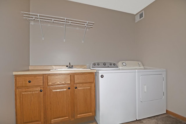 laundry area with visible vents, cabinet space, a sink, separate washer and dryer, and baseboards