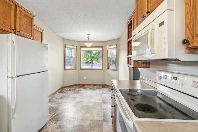 kitchen featuring white appliances, baseboards, brown cabinetry, decorative light fixtures, and a textured ceiling