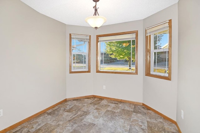 unfurnished room with stone finish flooring and baseboards