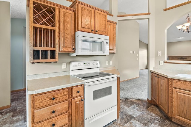 kitchen featuring brown cabinets, light countertops, an inviting chandelier, white appliances, and baseboards