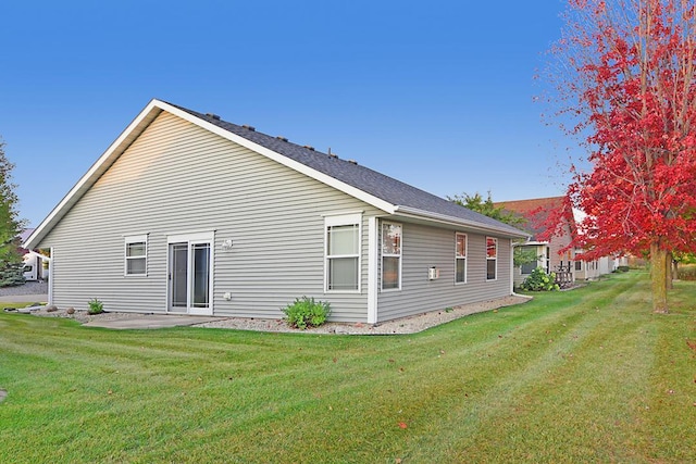 view of side of property featuring a patio area and a lawn