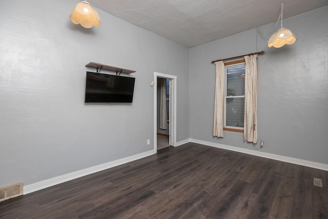 unfurnished room featuring visible vents, baseboards, and dark wood-style floors