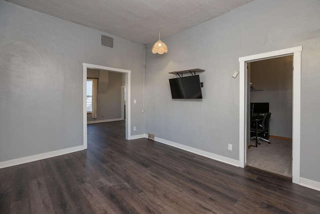 spare room featuring a textured ceiling, baseboards, visible vents, and dark wood-style floors