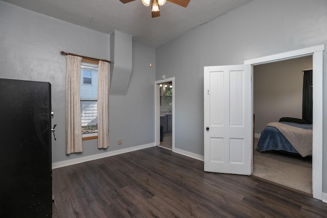 unfurnished bedroom featuring ceiling fan, wood finished floors, high vaulted ceiling, baseboards, and ensuite bath