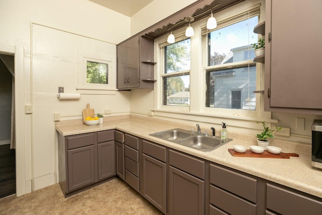 kitchen featuring light countertops, gray cabinets, a sink, and stainless steel microwave