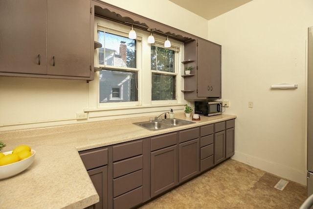 kitchen featuring a sink, light countertops, gray cabinets, baseboards, and stainless steel microwave