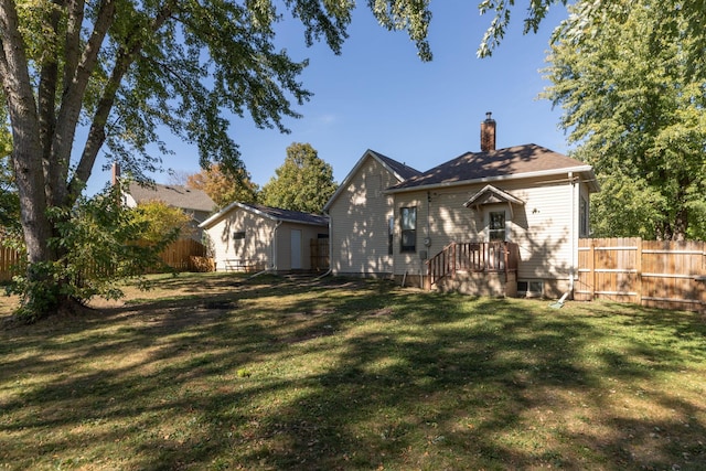 back of property featuring fence, an outbuilding, a chimney, and a yard