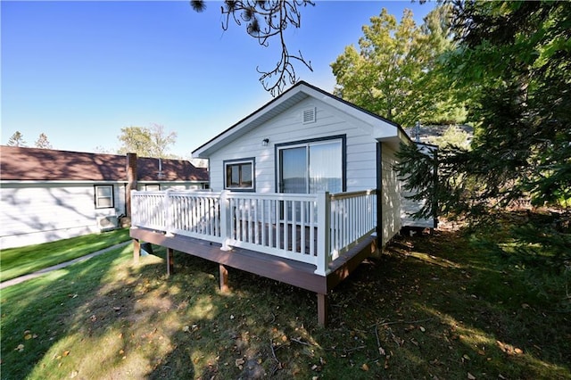 rear view of house featuring a wooden deck and a yard