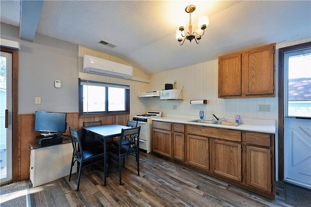 kitchen featuring brown cabinets, an AC wall unit, white appliances, and under cabinet range hood