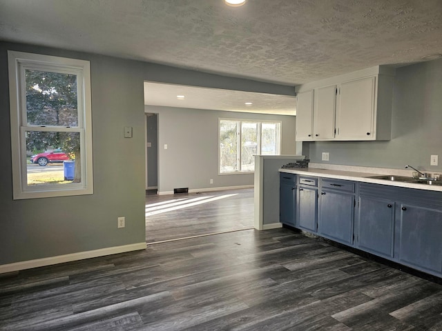 kitchen with white cabinets, a textured ceiling, dark wood-type flooring, sink, and blue cabinets