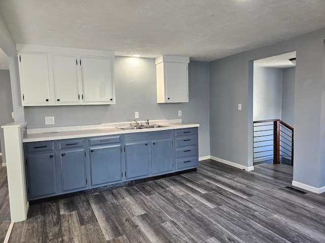 kitchen featuring dark hardwood / wood-style floors, white cabinets, sink, and a textured ceiling