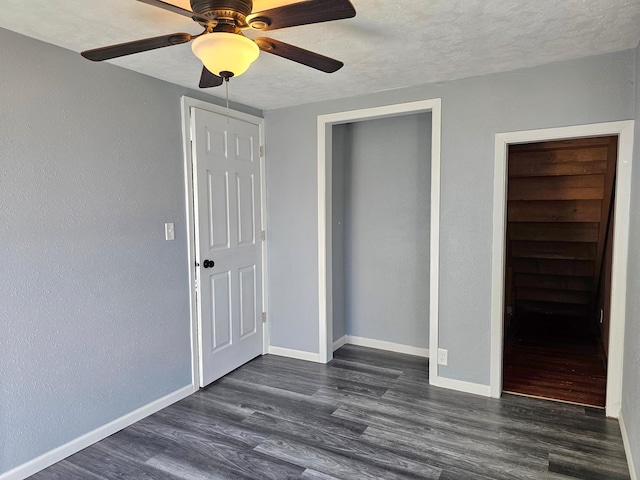 unfurnished bedroom with a closet, ceiling fan, a textured ceiling, and dark hardwood / wood-style flooring