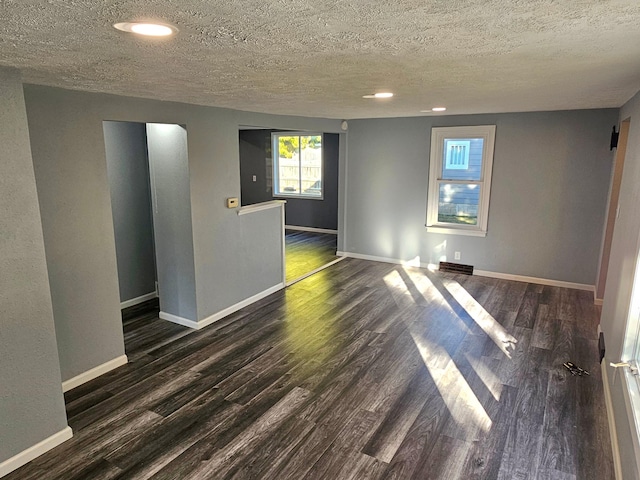 unfurnished room with dark wood-type flooring and a textured ceiling