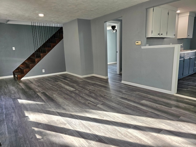 unfurnished living room featuring ceiling fan, a textured ceiling, and dark hardwood / wood-style flooring