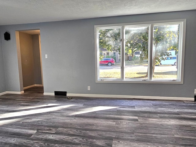 empty room with a textured ceiling and dark hardwood / wood-style flooring