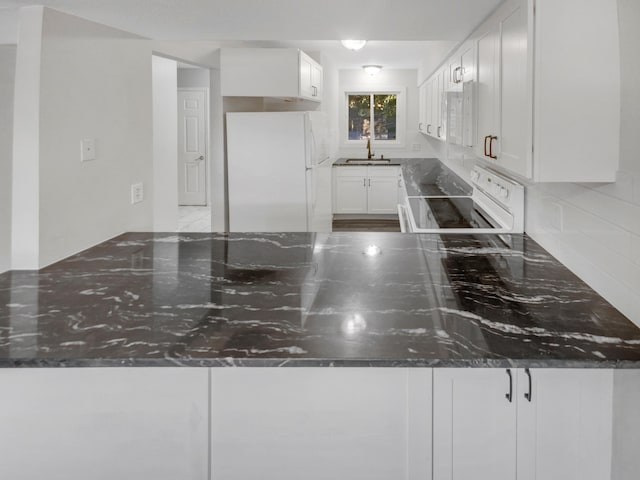 kitchen featuring white cabinets, sink, white appliances, backsplash, and dark stone counters