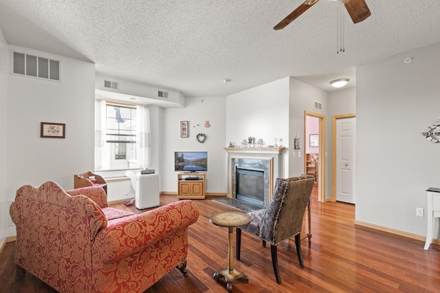 living room with a textured ceiling, a fireplace, hardwood / wood-style floors, and ceiling fan