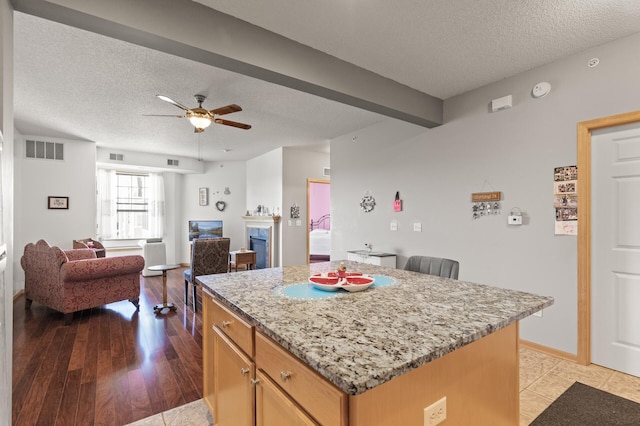 kitchen featuring a textured ceiling, a center island, ceiling fan, and light hardwood / wood-style flooring