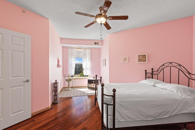 bedroom with ceiling fan, a textured ceiling, and dark hardwood / wood-style flooring