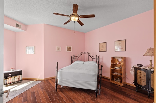 bedroom featuring ceiling fan, a textured ceiling, and dark wood-type flooring