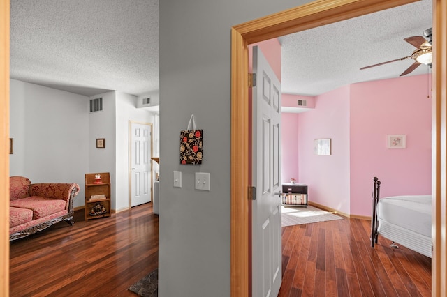 hallway with a textured ceiling and dark hardwood / wood-style floors