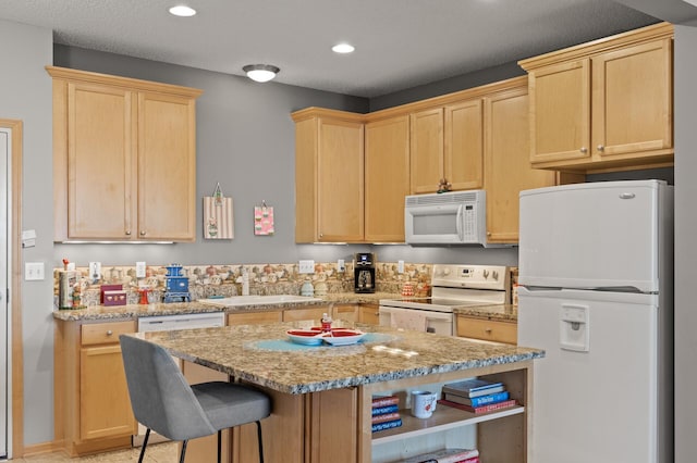 kitchen with white appliances, light brown cabinets, and light stone counters