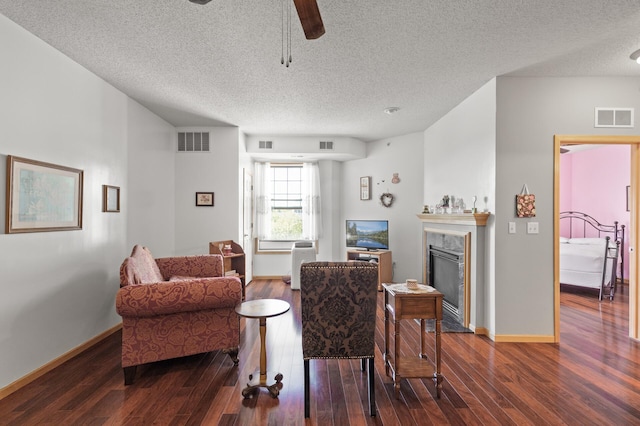 living room with a textured ceiling, dark hardwood / wood-style flooring, ceiling fan, and a premium fireplace