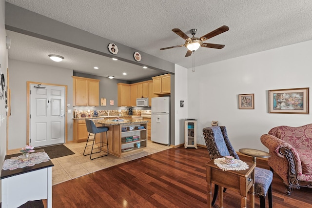 dining room with a textured ceiling, light hardwood / wood-style floors, and ceiling fan