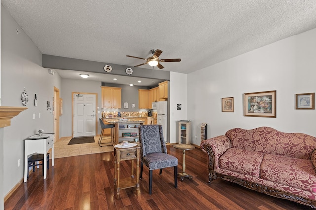 living room with a textured ceiling, wood-type flooring, and ceiling fan