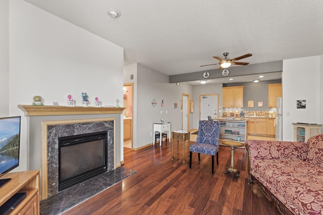 living room featuring a textured ceiling, a premium fireplace, ceiling fan, and dark hardwood / wood-style flooring