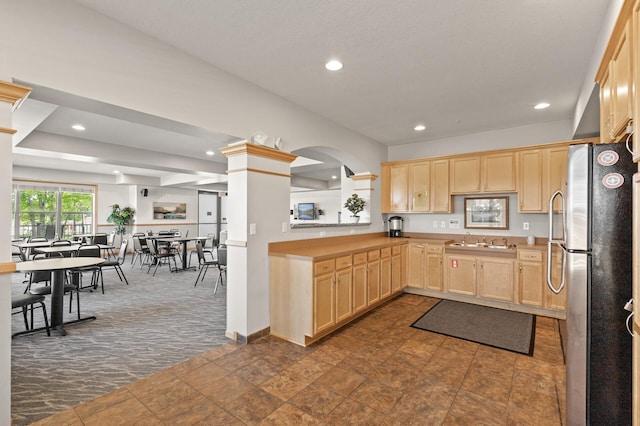 kitchen with light brown cabinets, stainless steel refrigerator, dark colored carpet, and sink