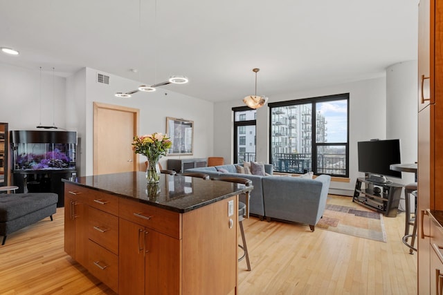 740 Portland Ave Unit 1207, Minneapolis, MN 55415 - kitchen with a kitchen island, open floor plan, light wood-type flooring, and dark stone counters