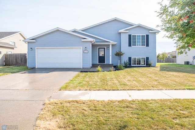 view of front of house featuring a garage, a front lawn, and central air condition unit