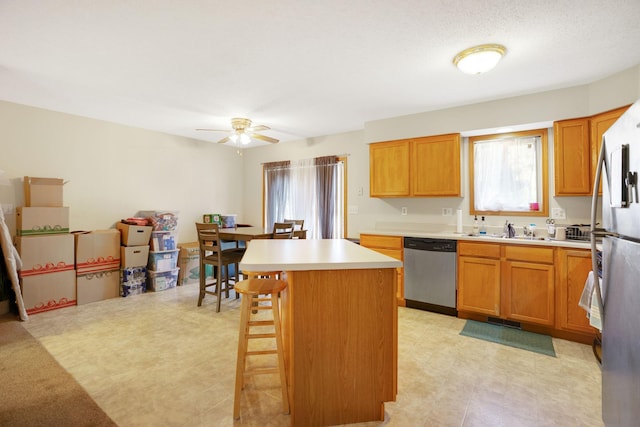 kitchen with a kitchen breakfast bar, a kitchen island, dishwasher, ceiling fan, and sink